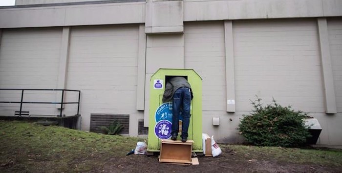  A man tries to retrieve items from a clothing donation bin in Vancouver, on Wednesday December 12, 2018. Clothing donation bins can return to the streets of Vancouver, as long as they meet a strict set of conditions. A statement from the City of Vancouver says councillors have approved new rules covering bins on city and private property. THE CANADIAN PRESS/Darryl Dyck