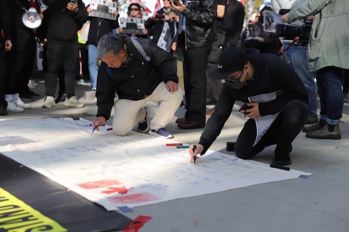  Supporters also wrote messages of support for Hong Kong protesters on a large white banner which will be taken back to Hong Kong. Photo by Herb Chao 