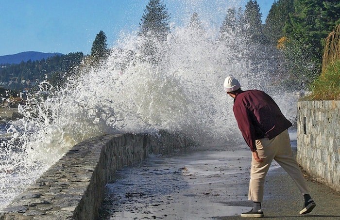  A walker seeks shelter from the angry sea as a fall storm blows into West Vancouver, on Friday. Photo by Linda Leigh McDougal
