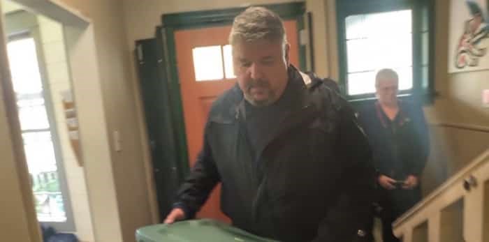  A member of B.C.'s Community Safety Unit lugs away a plastic crate filled with cannabis products from an unlicensed cannabis store on Thurlow Street | Photo: @DanaLarsen / Twitter