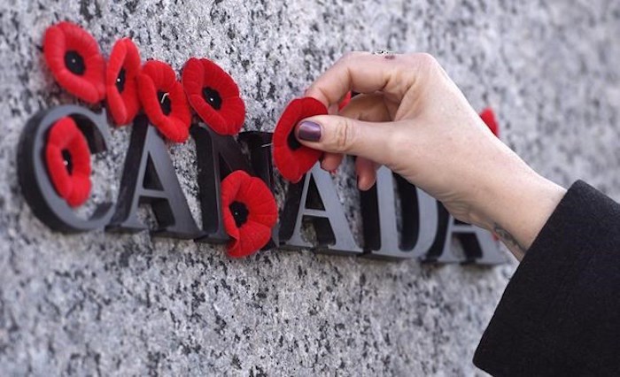  People place poppies over lettering in the National War Memorial during the National Remembrance Day ceremony in Ottawa on November 11, 2016. A new survey suggests more Canadians are planning to mark Remembrance Day this year, perhaps in a salute to the few remaining veterans of the Second World War. THE CANADIAN PRESS/Justin Tang