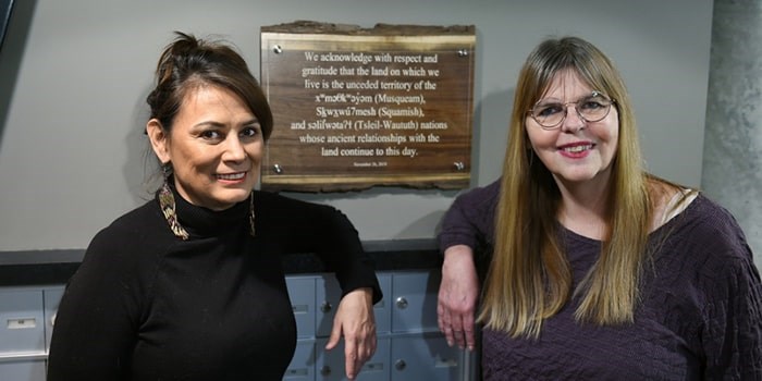  Beverley O’Neil and Carol Sill in the lobby of their condo building where a land acknowledgement sign has been posted. Photo: Dan Toulgoet