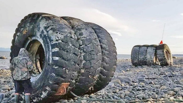  Lyle Adams walks next to some of the tires that have washed ashore at Shelter Bay. Photo courtesy Cherie Adams