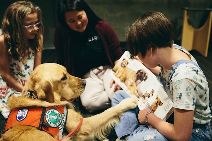  Golden retriever Abby listens while Annie Letheman (right) reads to her sister Ruby and researcher Camille Rousseau (middle) observes. Photo courtesy UBC Okanagan