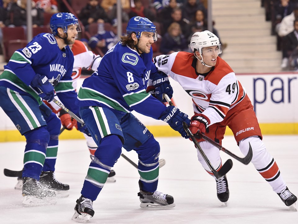 Alex Edler and Chris Tanev defend against the Carolina Hurricanes.