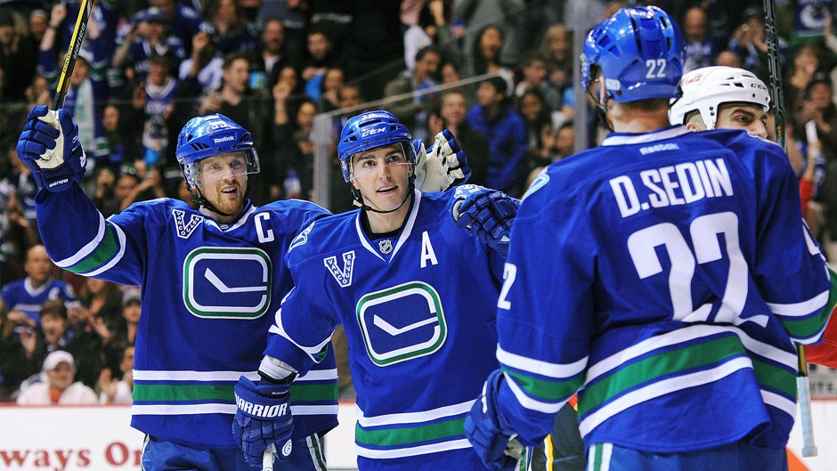 Daniel and Henrik Sedin celebrate a goal with Alex Burrows