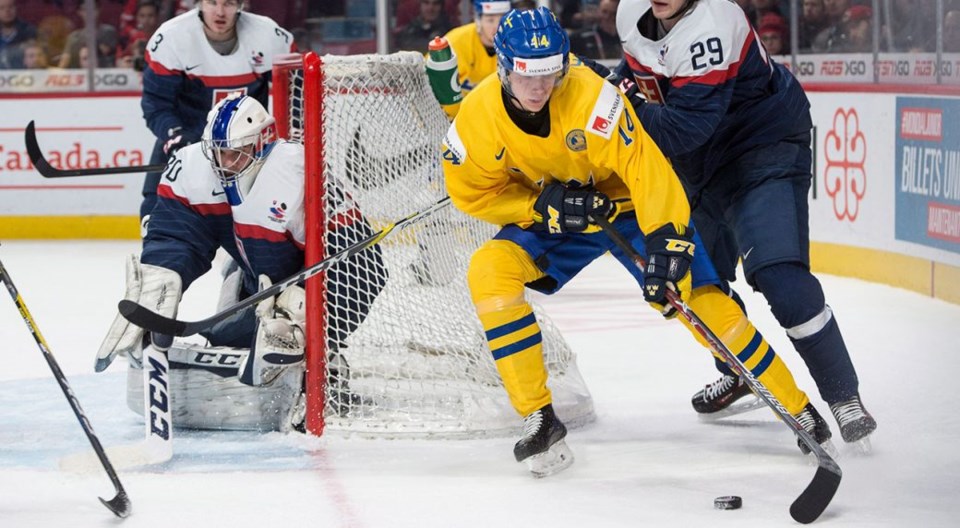 Elias Pettersson holds off a check at the 2018 World Juniors.