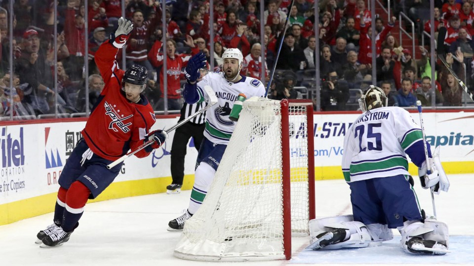 Evgeny Kuznetsov of the Capitals celebrates while Erik Gudbranson and Jacob Markstrom look on.