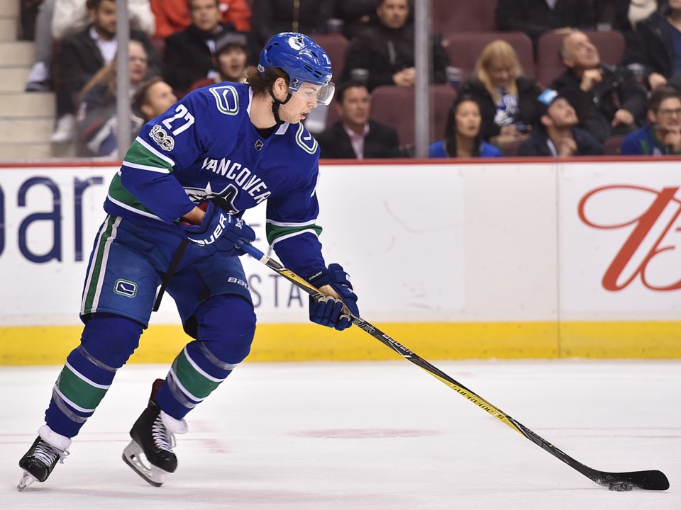 Ben Hutton looks down at the puck as he skates up ice for the Vancouver Canucks.