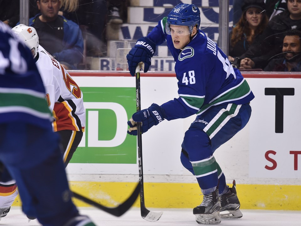 Olli Juolevi plays the puck for the Vancouver Canucks in preseason action against the Calgary Flames