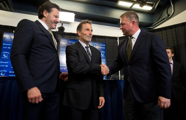 Mike Gillis shakes John Tortorella's hand as Francesco Aquilini looks on.