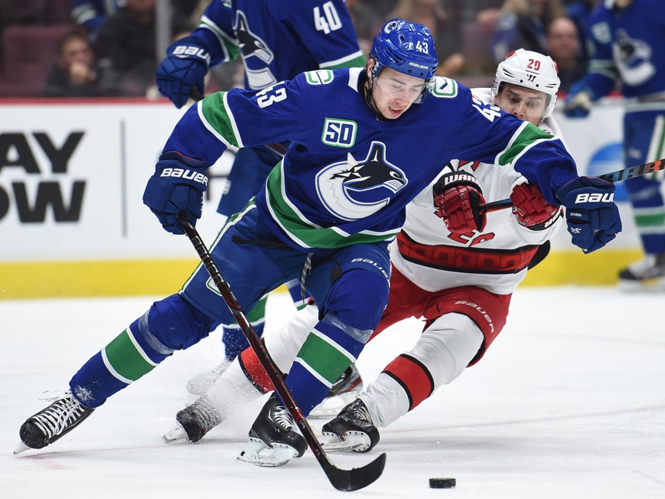 Quinn Hughes protects the puck from Sebastian Aho of the Carolina Hurricanes.
