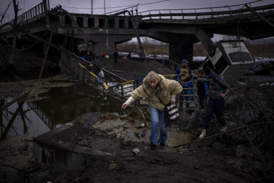 A woman runs as she flees with her family across a destroyed bridge in the outskirts of Kyiv, Ukraine, Wednesday, March 2. 2022. (AP Photo/Emilio Morenatti)