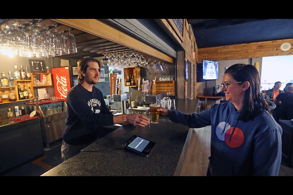 Bartender Jared Spencer pours a beer for Caitlin Bauer inside the bar at the Victoria Curling Club. ADRIAN LAM, TIMES COLONIST