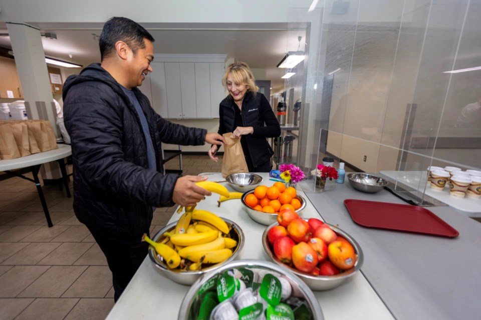 Volunteers Lyn de Sousa and Owen Dait prepare food bags at the Soup Kitchen at St. Andrew’s Cathedral. DARREN STONE, TIMES COLONIST