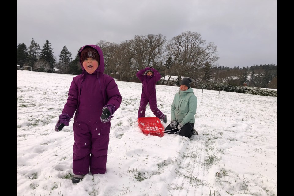 Snow is more than a sliding surface. Freshly fallen snow also tastes "good," says four-year-old Lucia, sledding Sunday, Dec. 26, 2021, with mom and dad and six-year-old sister Ella at Rockheights Middle School in Esquimalt. TIMES COLONIST