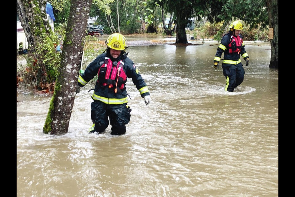 Members of the Dashwood Volunteer Fire Department wade through thigh-deep water as they go door-to-door to evacuate 200 homes along the Little Qualicum River. Dashwood Volunteer Fire Department 