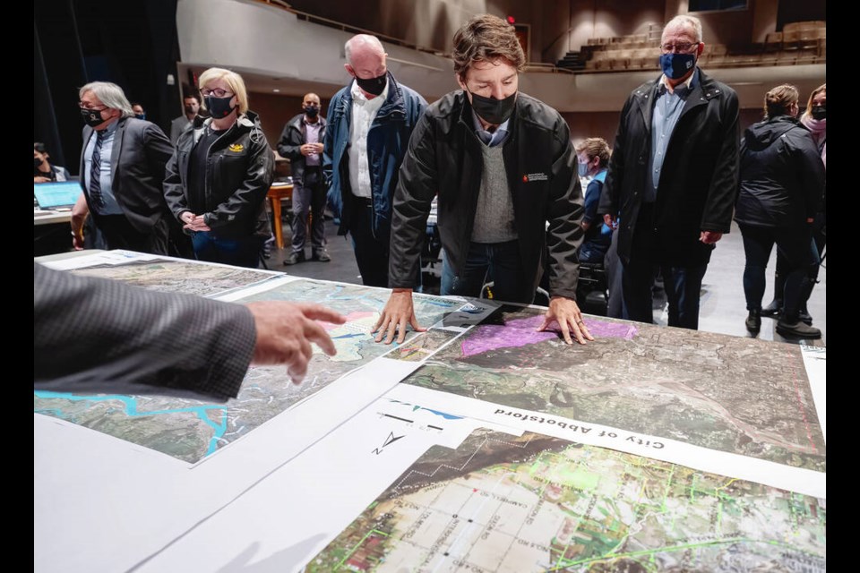 Prime Minister Justin Trudeau looks over maps as he surveys the damage left behind from the flood waters in Abbotsford, B.C., Friday, November 26, 2021. THE CANADIAN PRESS/Jonathan Hayward 