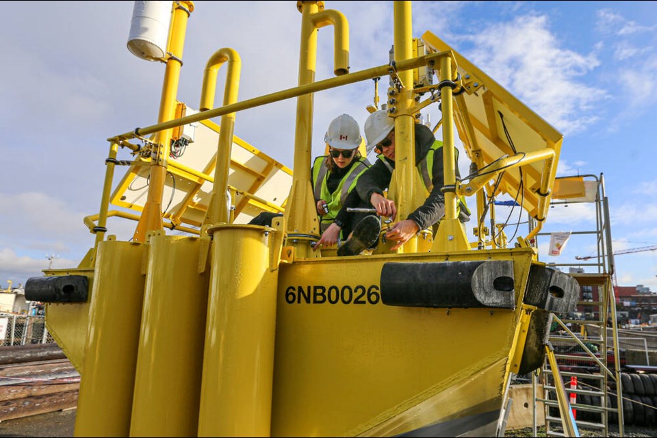 Research assistant Chloe Immonen, left, and Jules Paré work on the buoy, which measures wind speed and direction within a column that rises 200 metres above the water's surface, the same height as a typical offshore wind turbine. ADRIAN LAM, TIMES COLONIST 