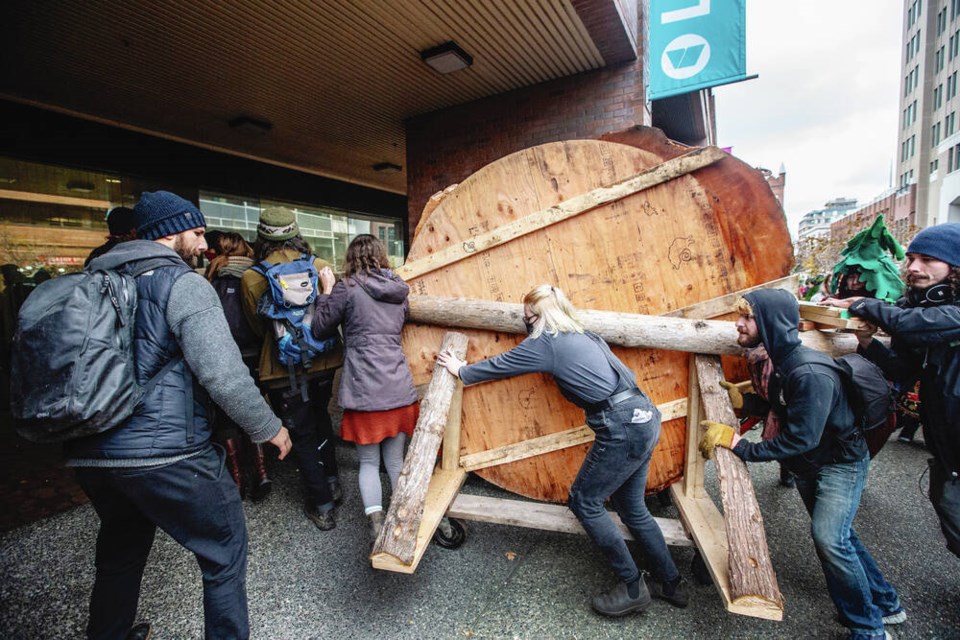 Fairy Creek protesters roll a slab of old-growth in downtown Victoria as part of a protest march. DARREN STONE, TIMES COLONIST. Nov. 24, 2021 
