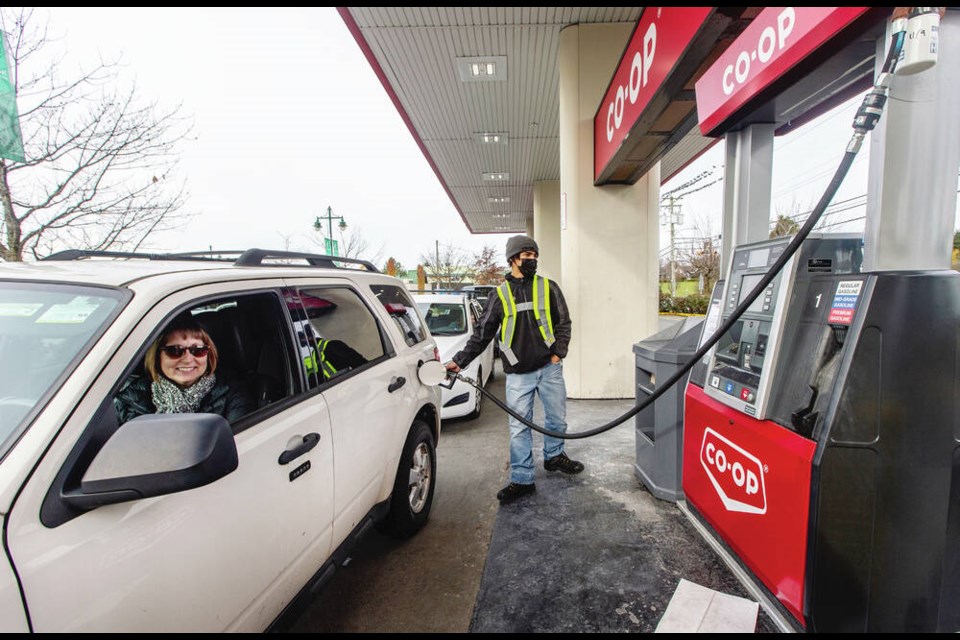 Peninsula Co-op gas attendant Malik Gagne-Smith fills the tank of Michelle MacDonald, who was at the front of the line after waiting two hours to gas up in Saanich on Saturday, Nov. 20, 2021. DARREN STONE, TIMES COLONIST 