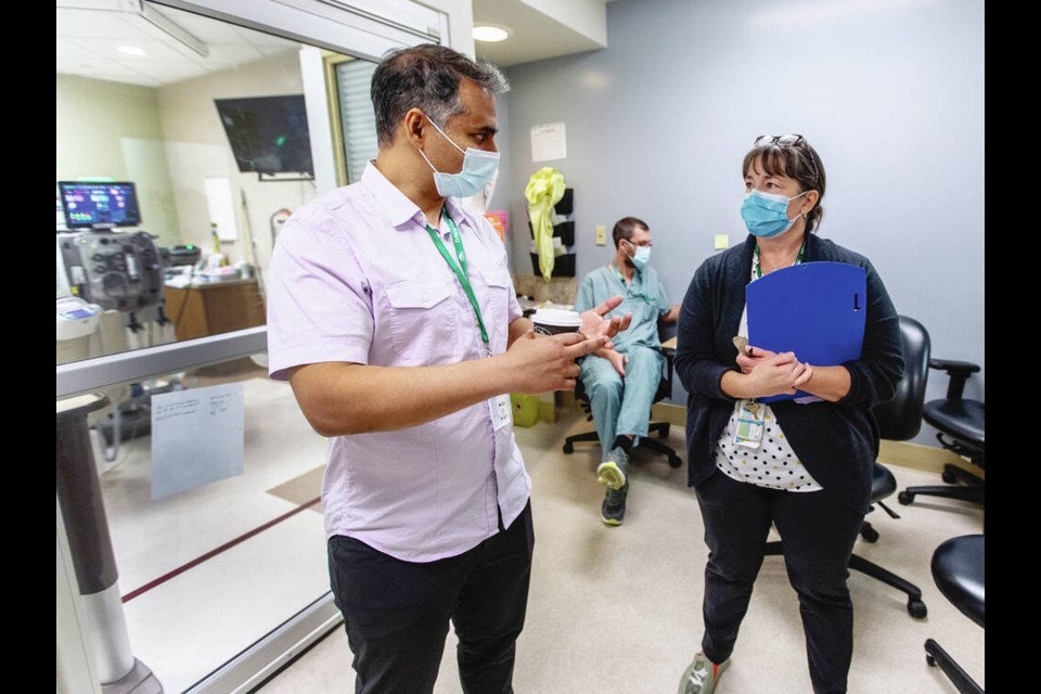 Dr. Omar Ahmad, department head for emergency and critical care for Island Health, talks to ICU registered nurse Carrie Homuth, who manages the adult intensive care unit and high-acuity unit for Royal Jubilee. DARREN STONE, TIMES COLONIST 