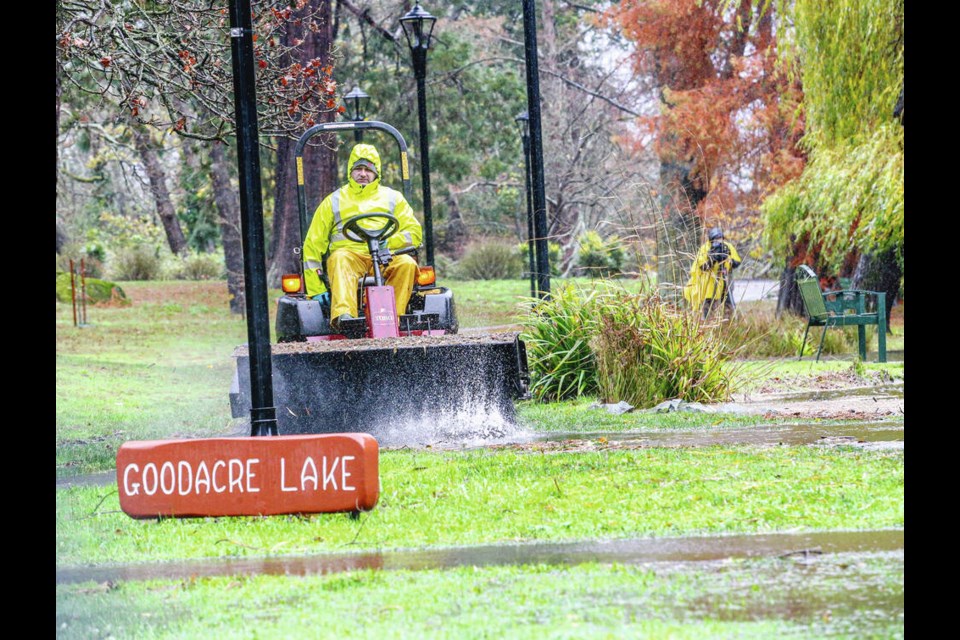 A City of Victoria employee pushes water from the side wall at Goodacre Lake in Beacon Hill Park, which overran its banks amid heavy rain. ADRIAN LAM, TIMES COLONIST 