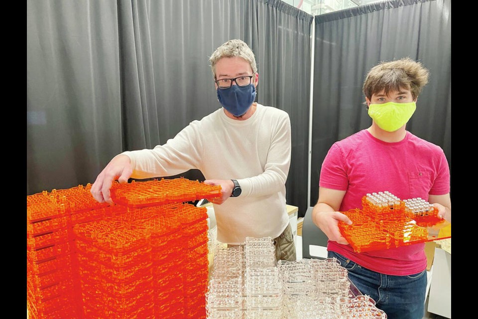 Matt Zeleny, left, and Kai Anderson show off Camosun Innovates' colour-coded trays for vials containing Pfizer COVID-19 vaccine doses. The bright orange trays with children's doses are easily distinguished from the clear trays with youth and adult doses. CAMOSUN COLLEGE 