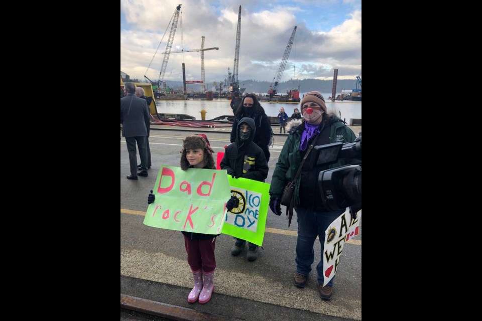 Athena Stone and Ethan Stone hold signs to welcome their dad, Andy, back home after a mission on HMCS Winnipeg. With them is grandmother Therese Stone, right, and mom Melissa, rear. 