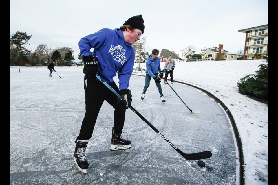 Tyler Rowe, foreground, Kai Walsh and Kyle Erickson play hockey on Harrison Yacht Pond off Dallas Road on a cold and snowy day in Victoria. ADRIAN LAM, TIMES COLONIST. Dec. 27, 2021 