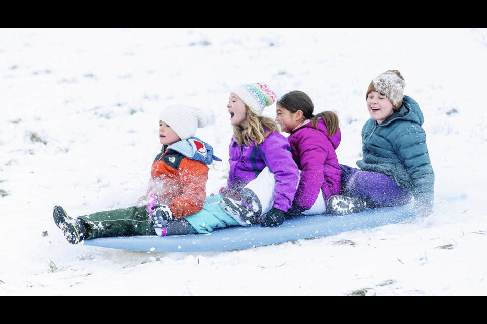 Six-year-old Hayden, left, and Poppy Van Cadsand, 8, with Annika Filuk, 8, and Mahlin Grant, 8, have fun sledding down the hill at Beacon Hill Park on Tuesday. More snow is expected tonight and frigid temperatures are forecast to last until at least Thursday. ADRIAN LAM, TIMES COLONIST Dec. 28, 2021 