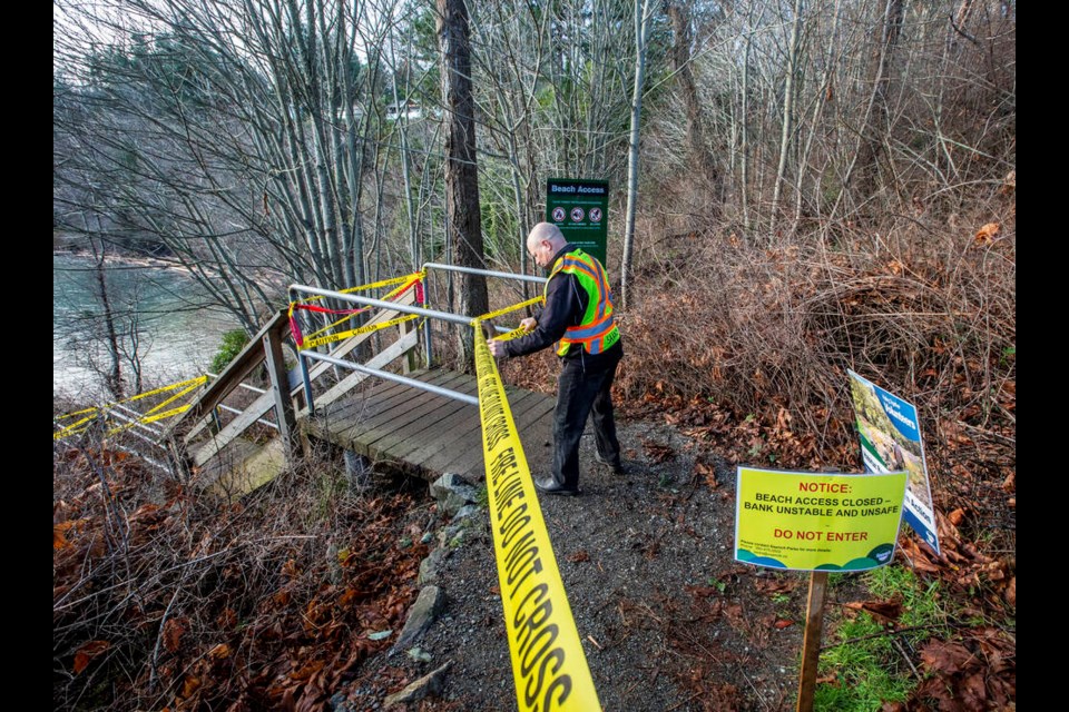 Saanich Parks worker Mike Goldsworthy puts up signs and tape at the entrance to stairs to the beach in Arbutus Cove Park in December. DARREN STONE, TIMES COLONIST 
