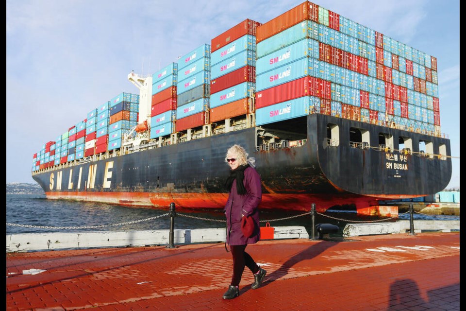 Veronica Strong-Boag and dog Annie walk past the container ship SM Busan at Ogden Point docks on Tuesday. ADRIAN LAM, TIMES COLONIST 
