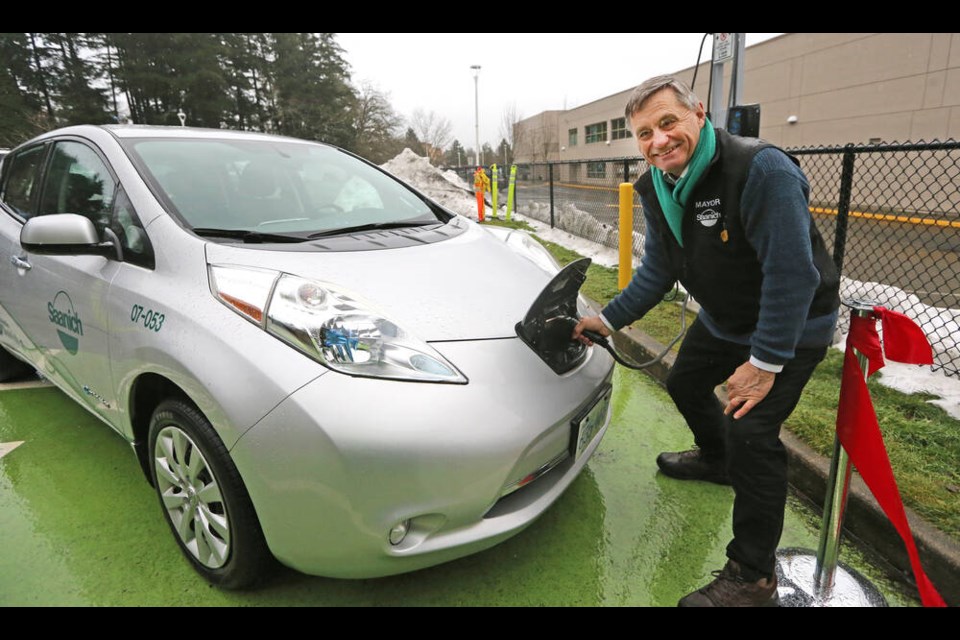 Saanich Mayor Fred Haynes powers up an electric vehicle at a new public charging station at Saanich Commonwealth Place, one of 20 new charging stations in the district. ADRIAN LAM, TIMES COLONIST 