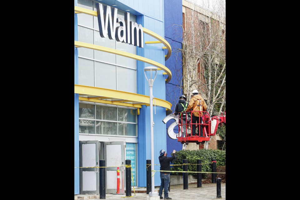 Blake Styan, left, hands an a to Dylan Rous, centre, and Cassidy Starck, as Triad Signs installs the Walmart sign at Hillside Shopping Centre on Wednesday. ADRIAN LAM, TIMES COLONIST 