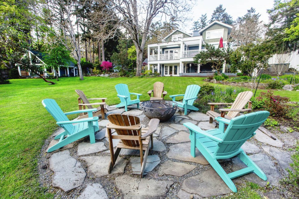 Turquoise and naturally weathered chairs provide a lively contrast around the fire pit at the side of the old woodshed, now converted into a bunk house. DARREN STONE