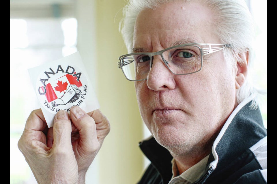 Graphic artist Victor Crapnell with the Take Back Our Flag sticker he designed. ADRIAN LAM, TIMES COLONIST 