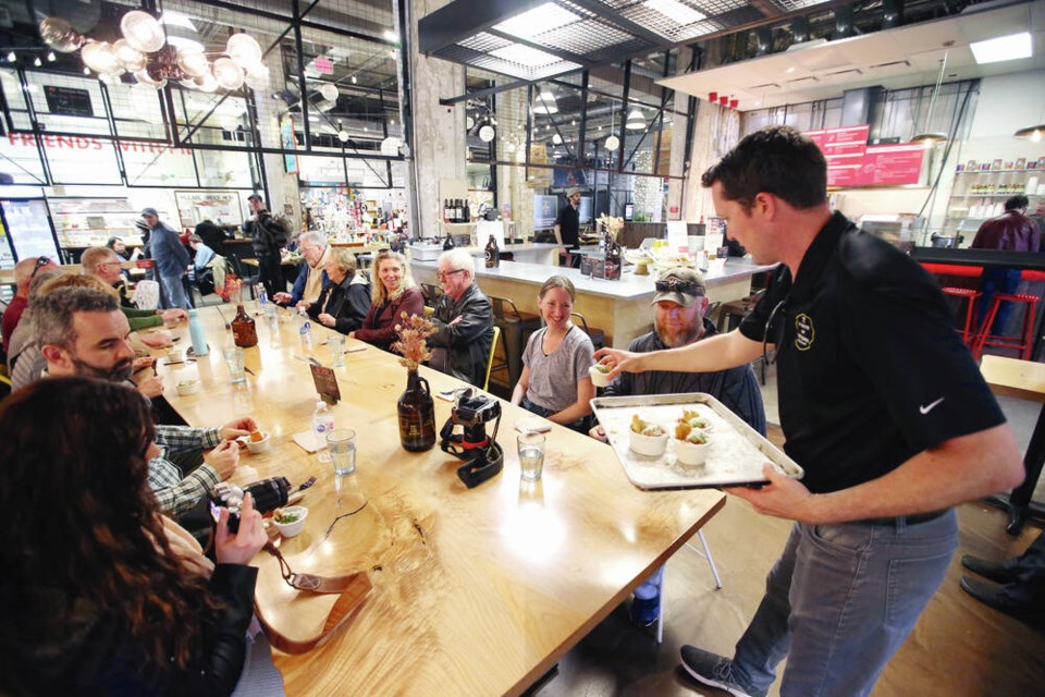 A group on a Taste of Victoria Food Tour led by Andy Olson samples meatballs from Roast restaurant in Hudson Market on Tuesday. After two years of ups and downs due to the pandemic, Olson is reporting bookings slightly above his 2019 numbers. ADRIAN LAM, TIMES COLONIST 