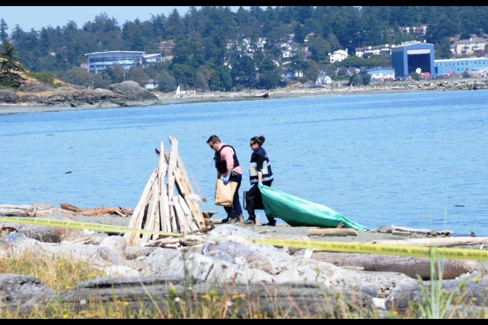 West Shore RCMP remove a tarp from the beach at Esquimalt Lagoon before clearing the scene where a body was discovered Thursday. Police are investigating the incident and asking for information from anyone who was in the area and saw anything suspicious. NINA GROSSMAN