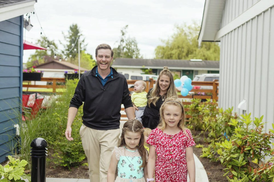 Parents Travis and Sabrina lead their children Everly, 5, left, Ellaina, 7, Lincoln, 2 (hidden), and Landon, nine months, to their new home at Habitat for Humanity Victoria's new 10-unit multi-family complex in North Saanich on Wednesday. Via Habitat for Humanity Victoria