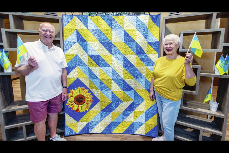 Don Ross, left, and Angie Chan show the Ukraine-inspired quilt they and two other quilters at Tapestry at Victoria Harbour made. DARREN STONE, TIMES COLONIST 