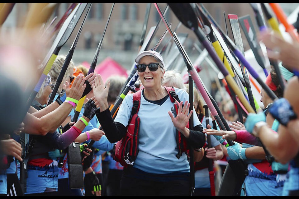 Helen Saulnier goes under the paddle tunnel, as cancer survivors take part in the ceremonial carnation toss during the Victoria Dragon Boat Festival at Victorias Inner Harbour on Saturday. ADRIAN LAM, TIMES COLONIST 