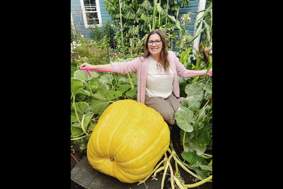 Carmen Spagnola holds out the tape she uses to take measurements of the giant pumpkin growing in the front yard of her home. TIMES COLONIST 