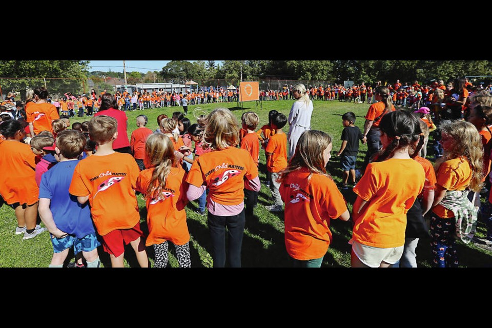 Students at George Jay Elementary form a circle around a bulletin board on which each student put a hand they drew as a show of  "helping hands." ADRIAN LAM, TIMES COLONIST 