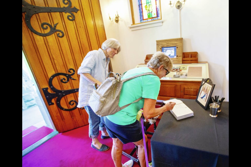 Heidi Davis, left, and Gaye Stone sign the book of condolences for the Queen at Government House on Thursday. DARREN STONE, TIMES COLONIST 