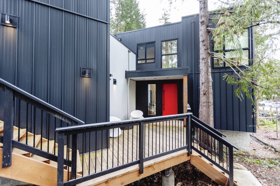 The front door entrance features a unique sculptural outdoor chair and bold red door. DARREN STONE, TIMES COLONIST 