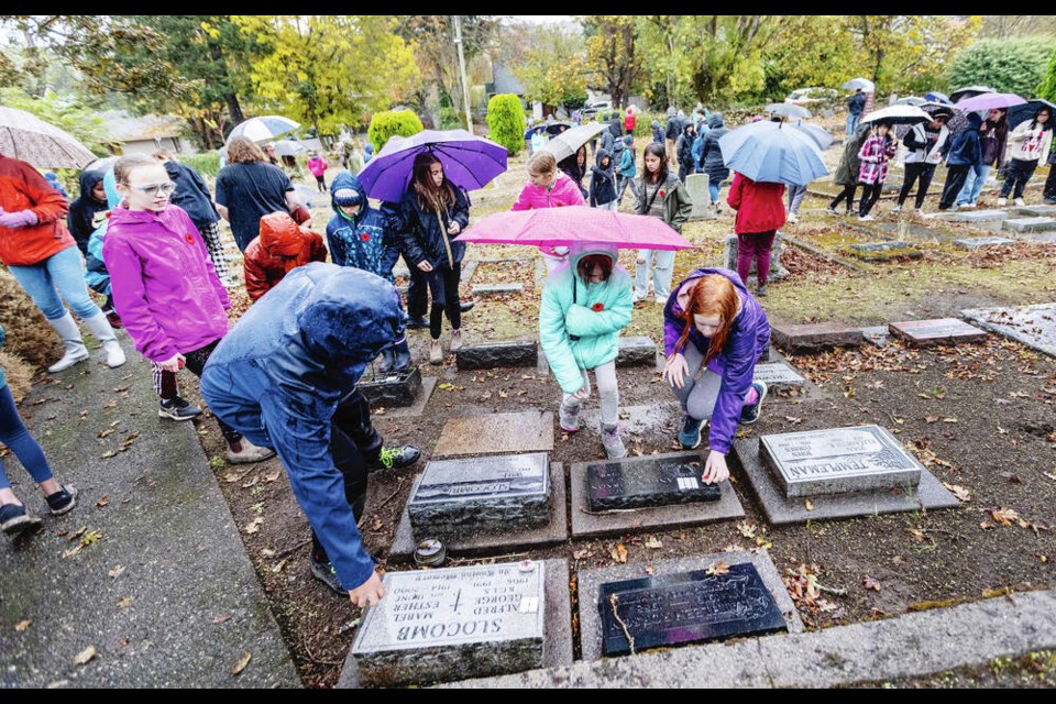 Students from Cedar Hill Middle School take part in a No Stone Left Alone ceremony Thursday at St. Lukes Cemetery, where stones painted with poppies were placed on graves of veterans. DARREN STONE, TIMES COLONIST 