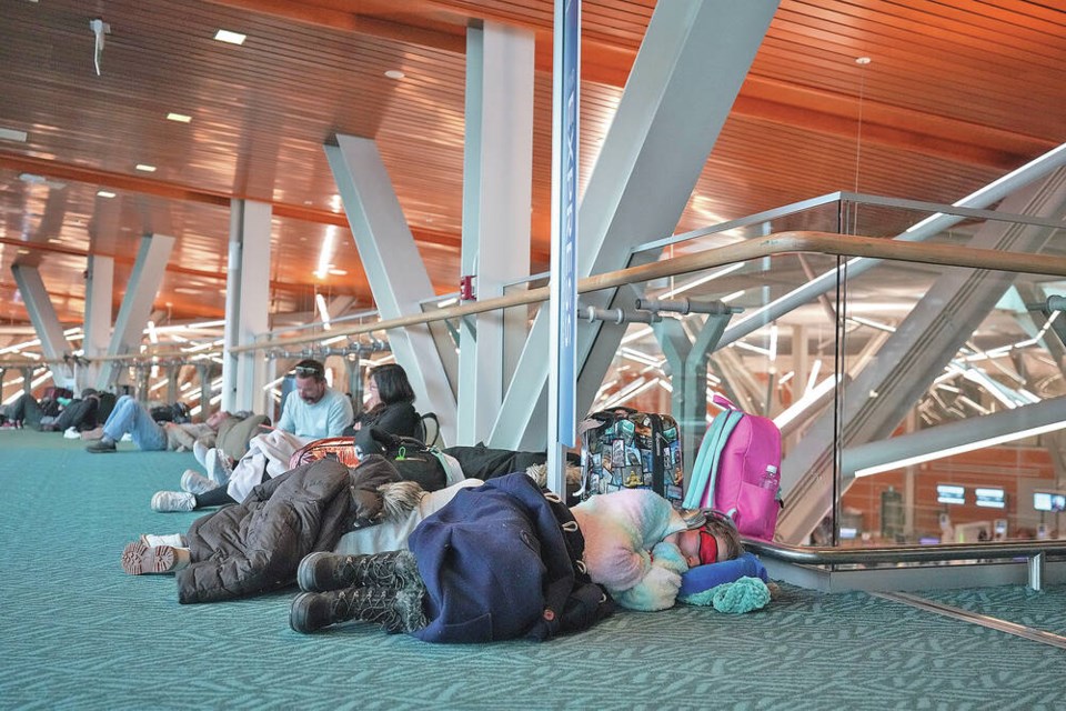A person sleeps on the floor at Vancouver International Airport after a snowstorm led to flight cancellations and major delays that stranded passengers in Richmond on Tuesday. PHOTOS BY DARRYL DYCK, CP 