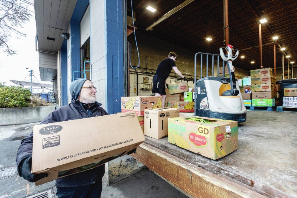 Earl Shaw, left, of Harbourview Church in Esquimalt picks up food with help from Berkley Rose at the Mustard Seed Street Church Food Security and Distribution Centre. DARREN STONE, TIMES COLONIST 