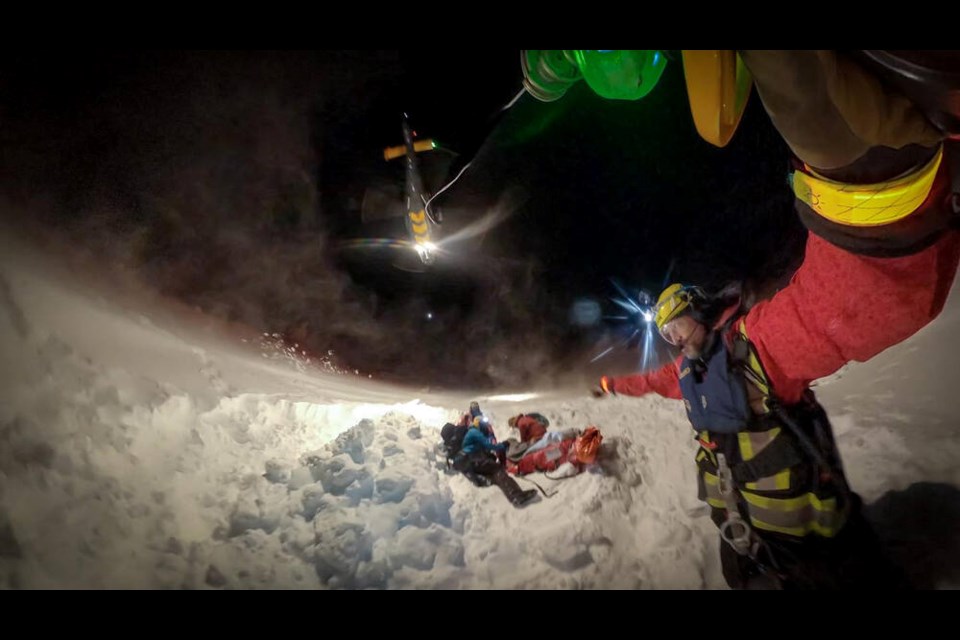 A North Shore Rescue technician drops from a helicopter as members of the Mount Cain Ski Patrol attend to an injured skier on Sunday night. Mount Cain is on the North Island, about 500 kilometres north of Victoria. NORTH SHORE SEARCH AND RESCUE 